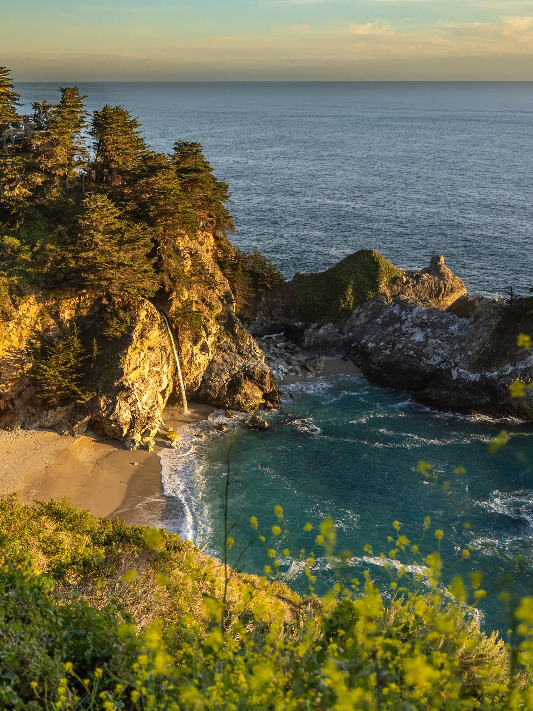 McWay Falls spilling onto the beach of a turquoise cove in Big Sur